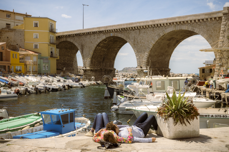 Un couple damoureux allongé sur un quai du port des Vallon des Auffes profite de la douceur du soleil de mai pour se relaxer.