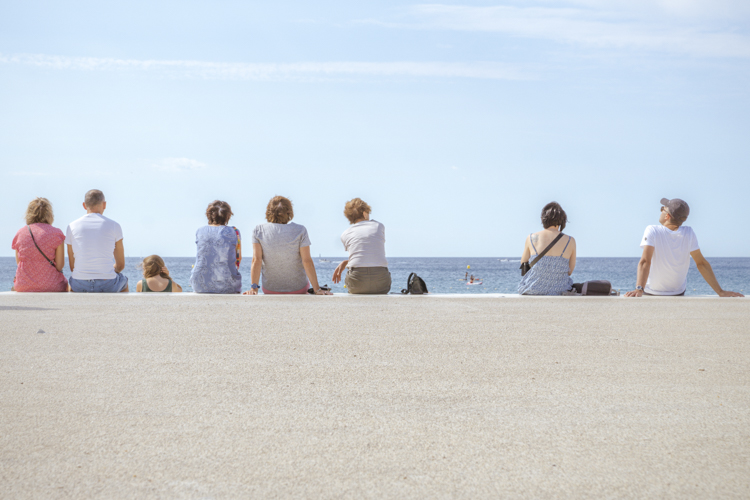 Un groupe de personnes assises face � la mer sur la plage de la Grande Mer. 