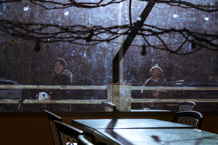 Deux femmes passant devant la b�che transparente d'une terrasse d'un caf�.