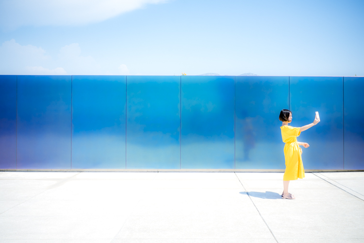 Une jeune femme v�tue d'une robe jaune, sur le toit-terrasse de la Cit� Radieuse du Corbusier se prenant en photo avec son t�l�phone.